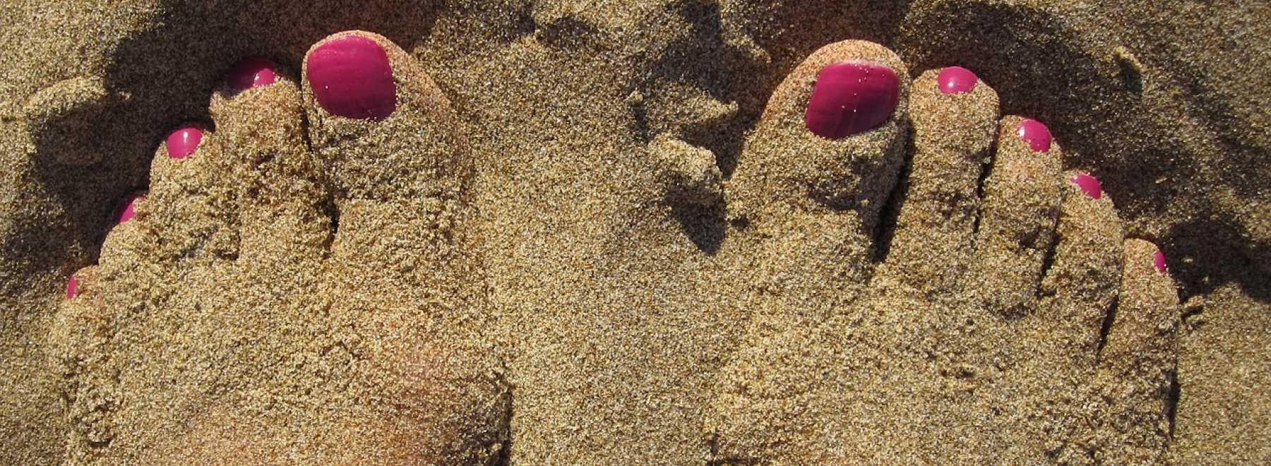 lackierte Zehen im Sand
