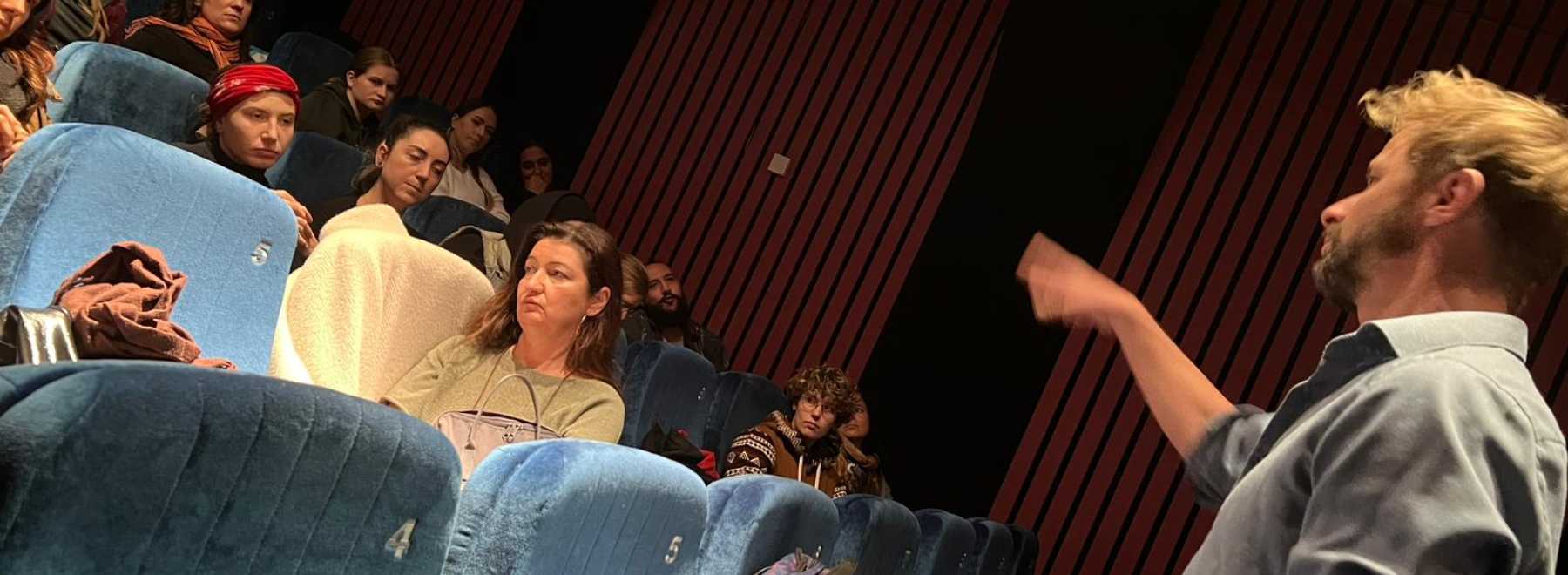 Lehrender diskutiert mit Studierenden im Kino